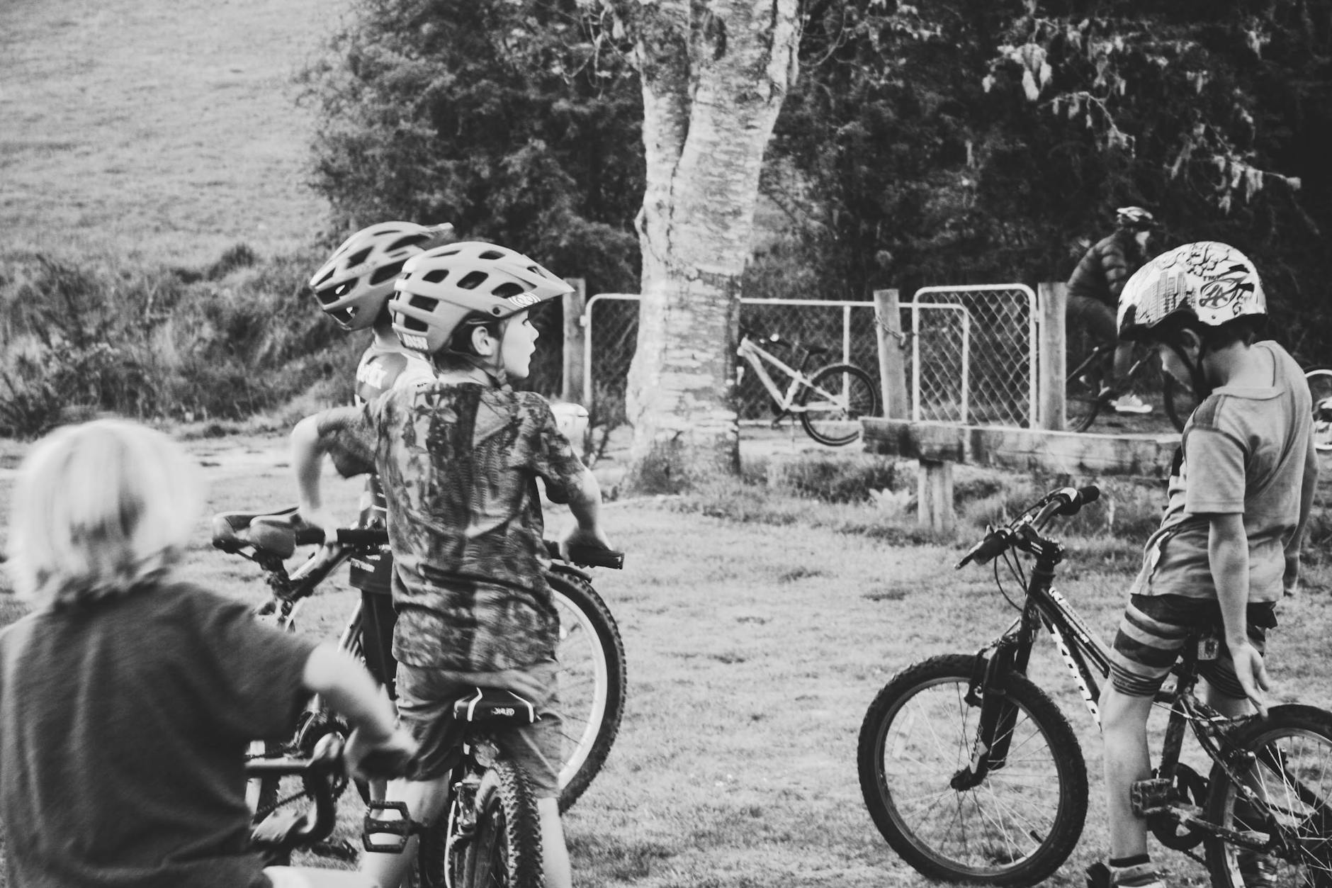 Children riding bicycles in a playful gathering, featuring a natural setting and helmets for safety.