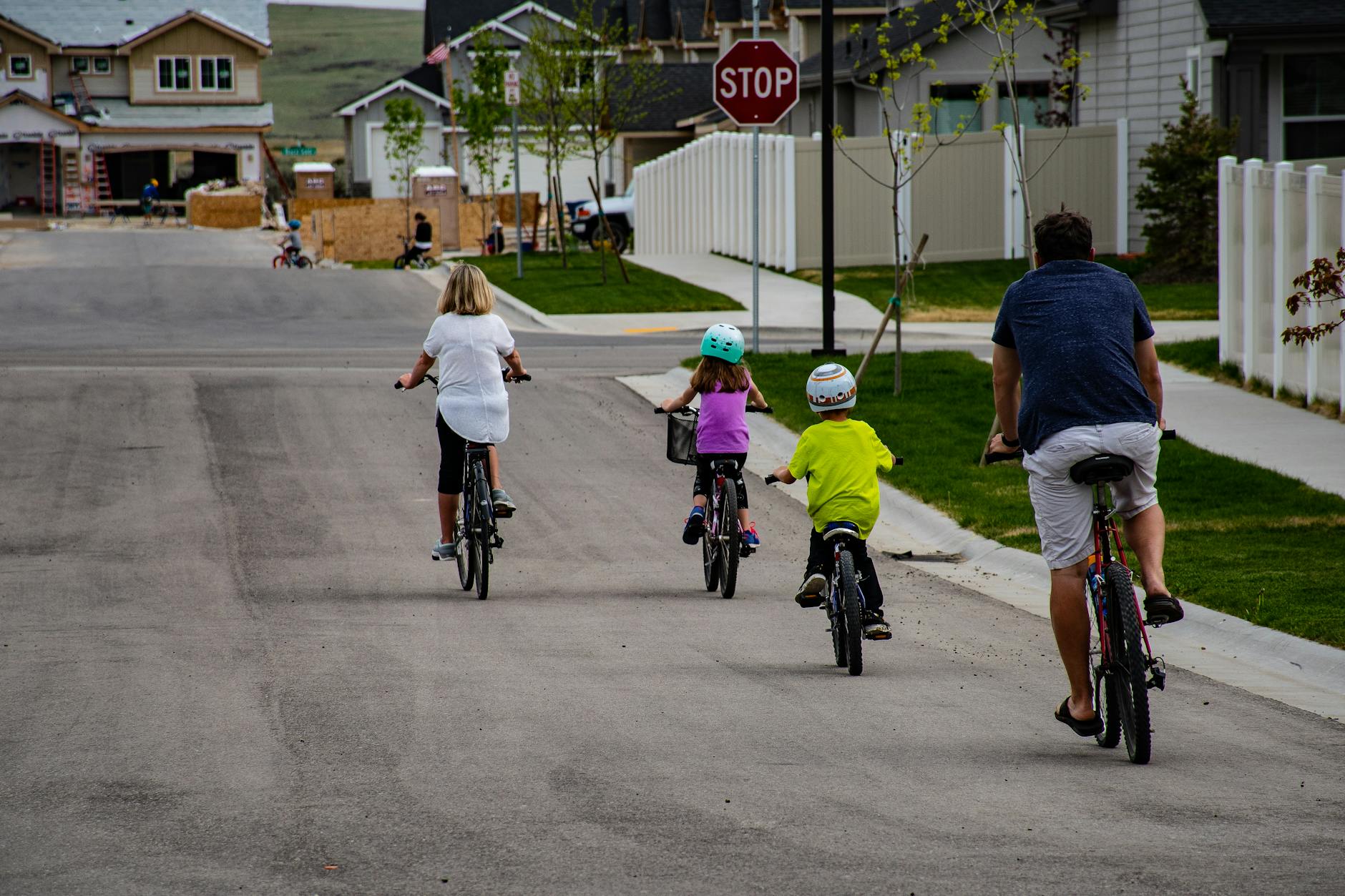 A family enjoys biking together on a suburban street, highlighting active outdoor lifestyle.