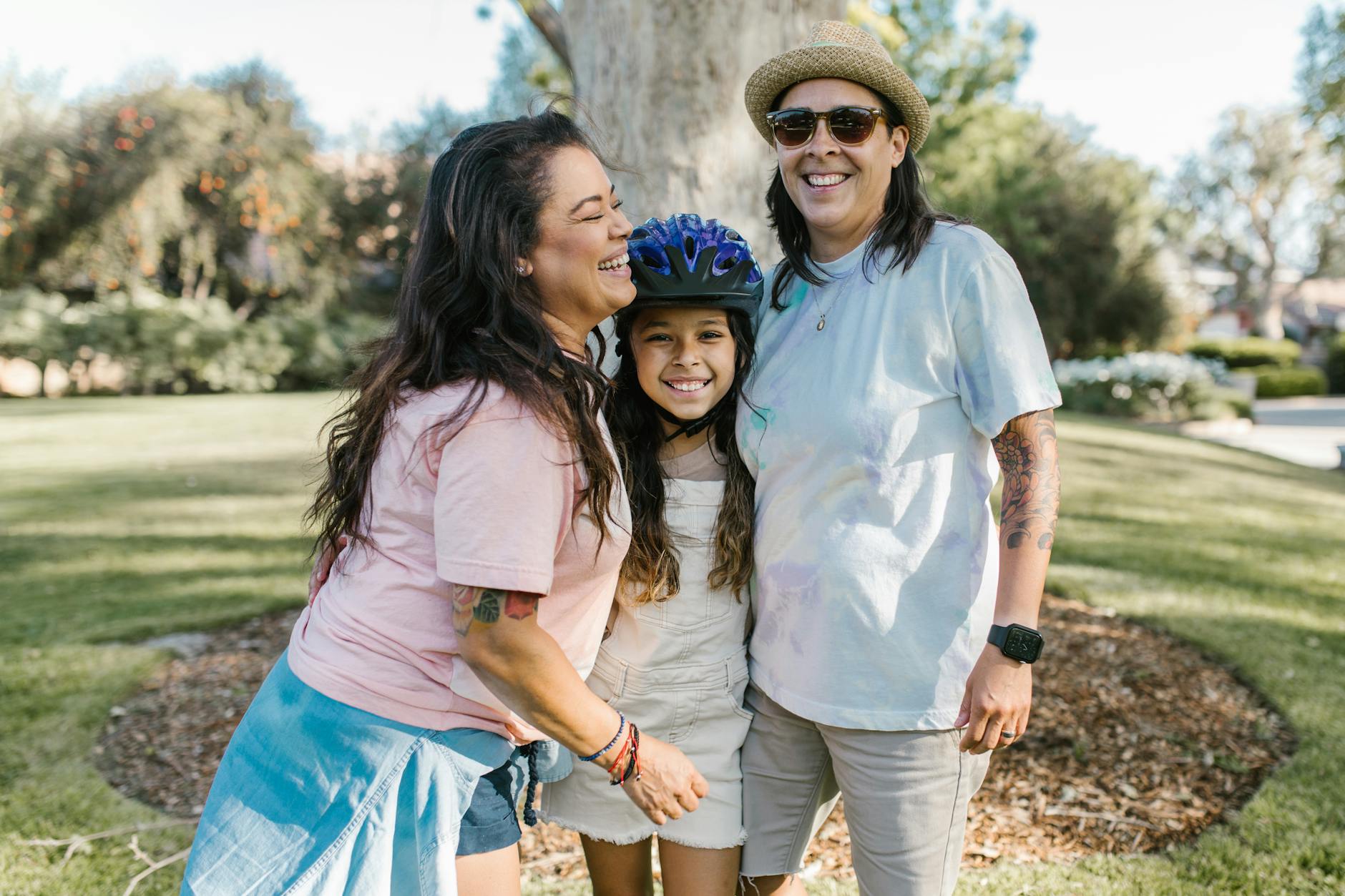 LGBTQ family enjoying a sunny day outdoors, representing love and togetherness.