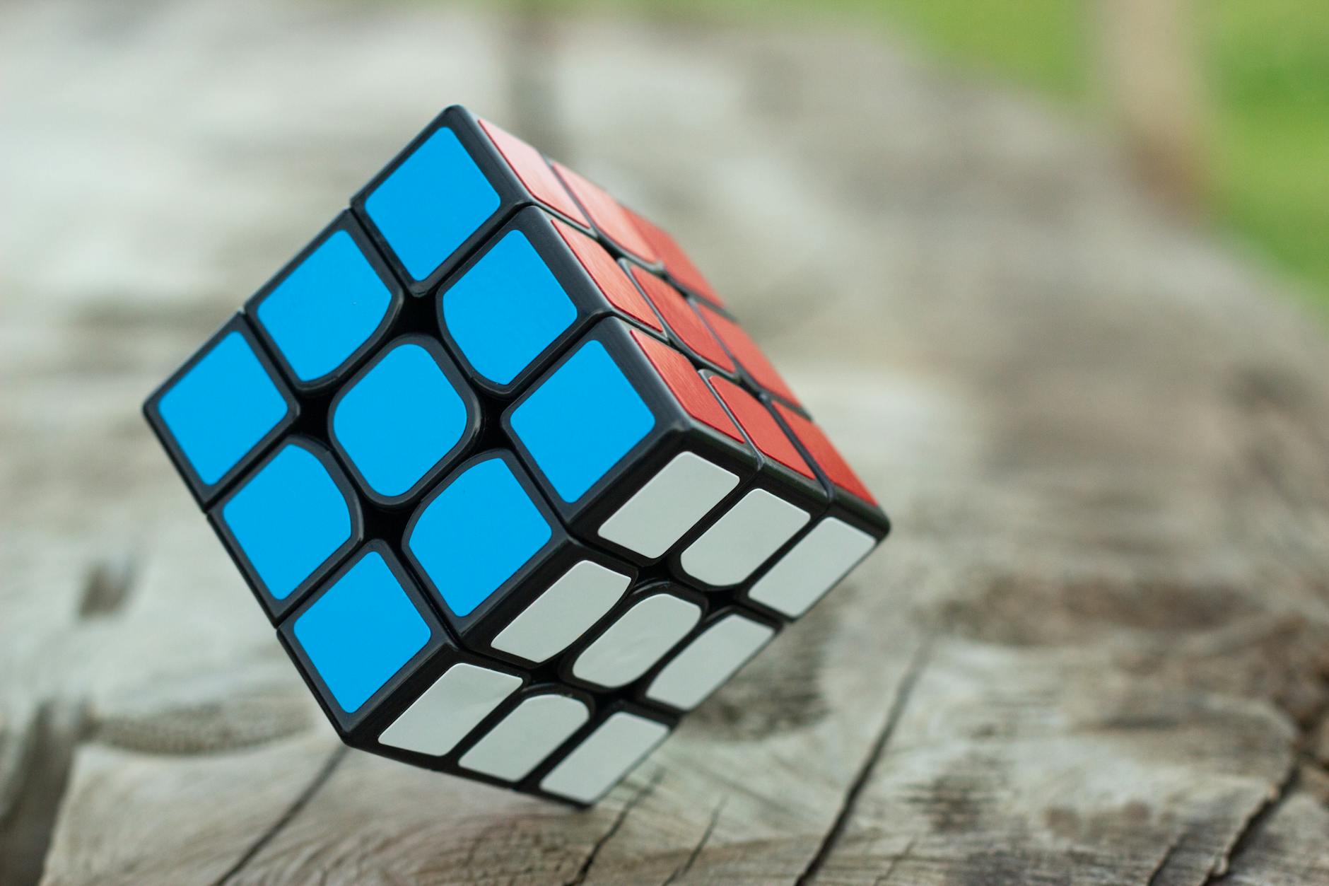 Colorful Rubik's Cube resting on a wooden surface, showcasing vibrant geometric patterns.