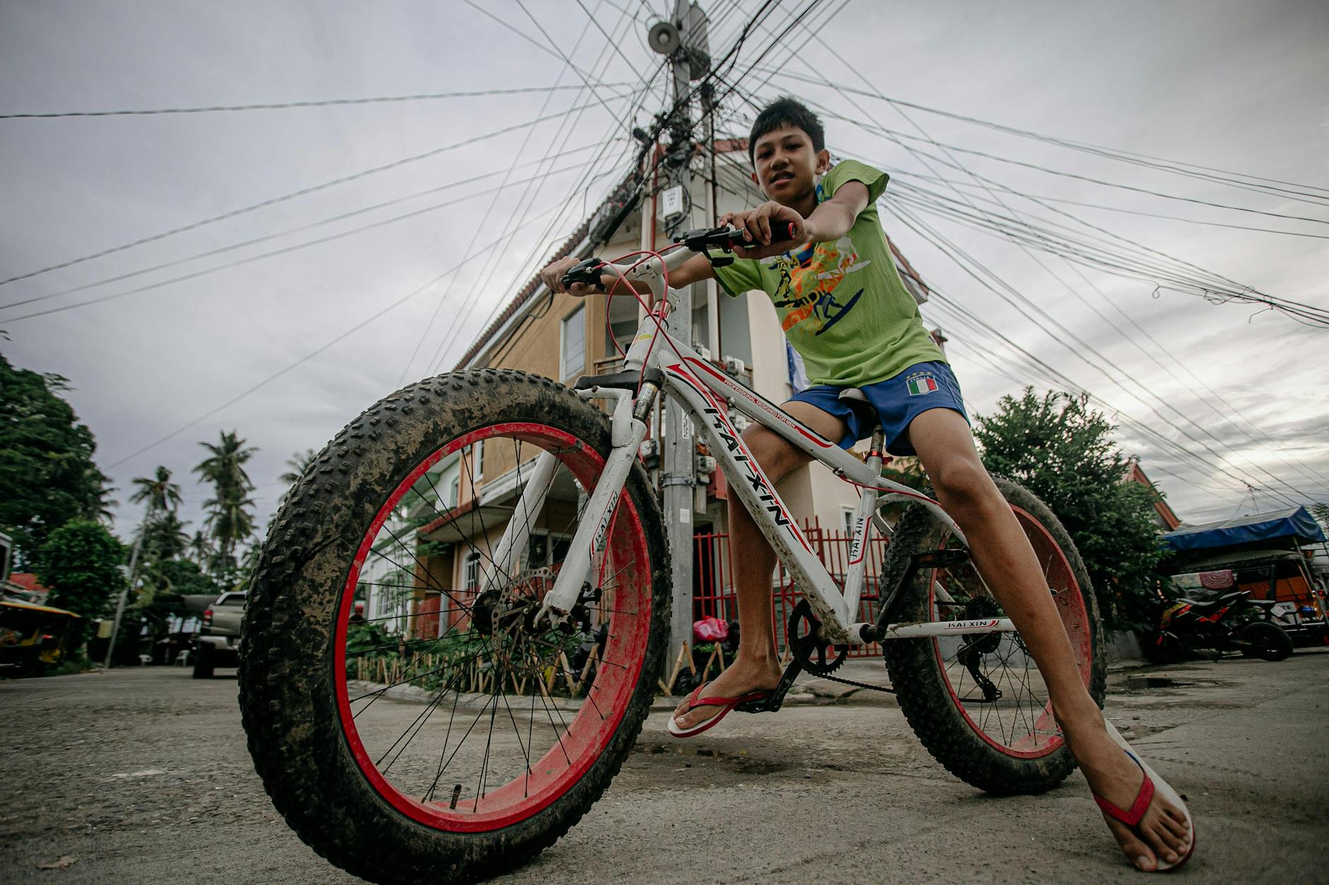 Teenage boy riding a fat-tire bike in a residential street, showcasing urban lifestyle.