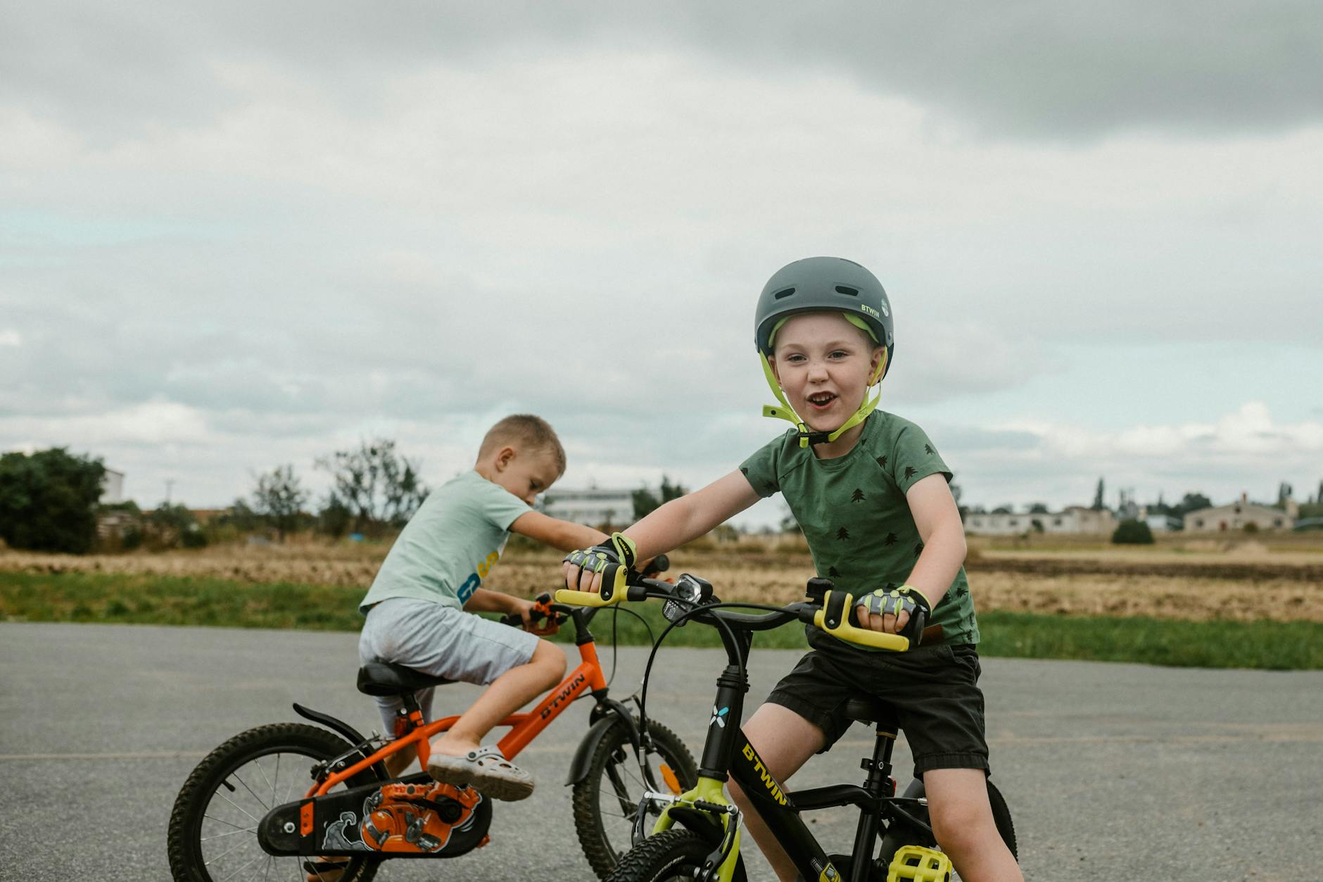 Two children riding bikes in a rural setting, showcasing active play.