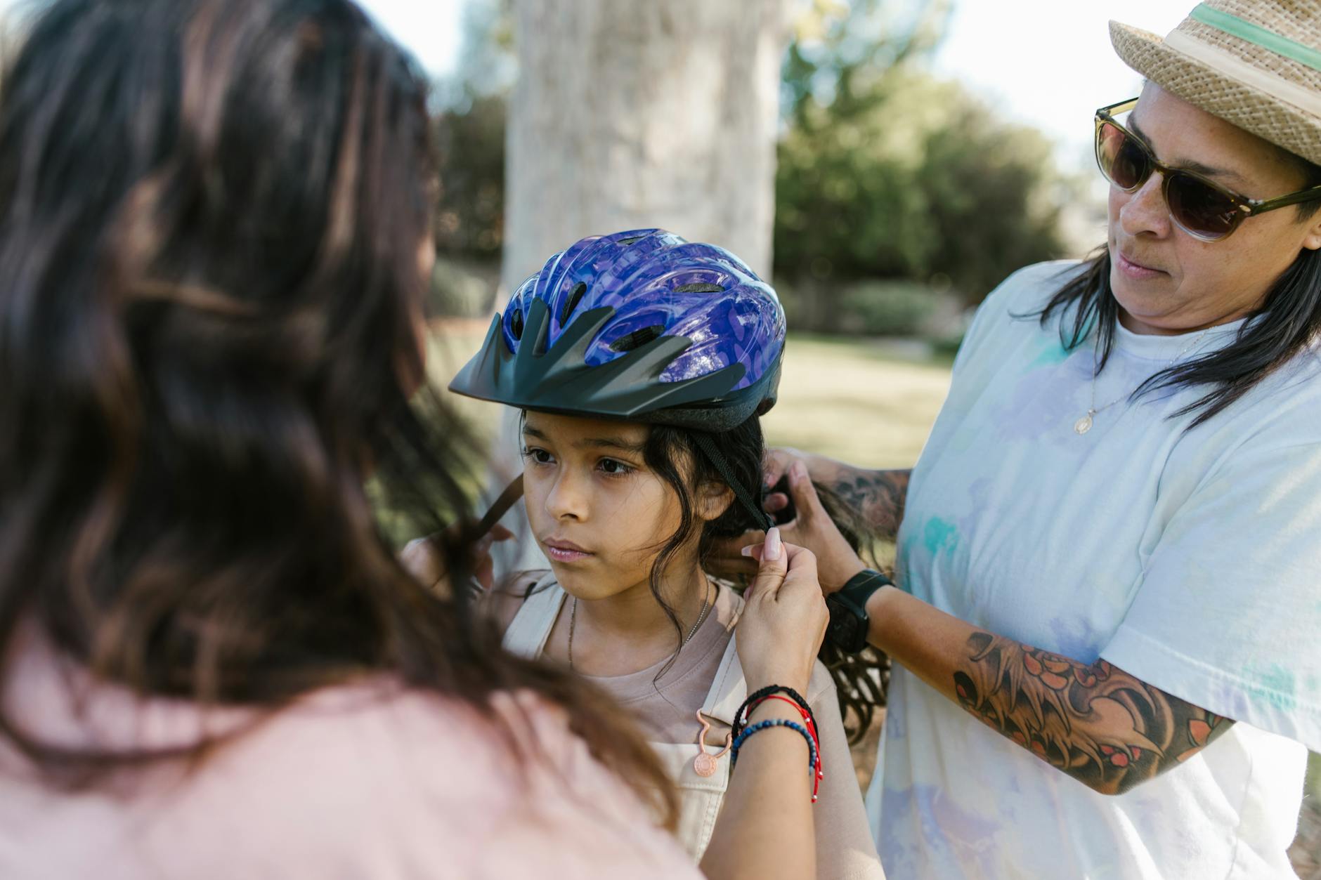 A caring moment of a parent adjusting a child's helmet outdoors, symbolizing safety and love.