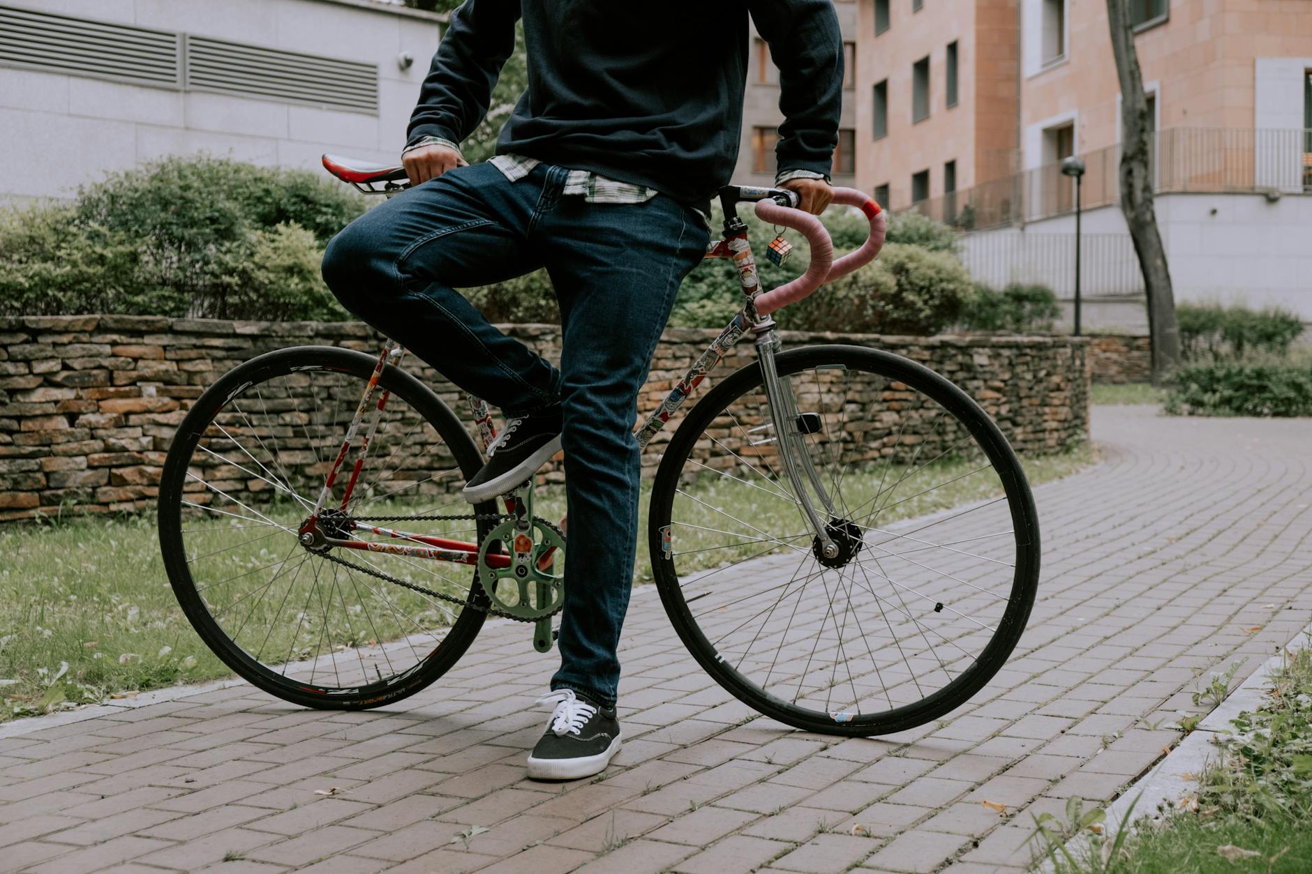 Casual scene of a man leaning on a bicycle outdoors on a paved path.