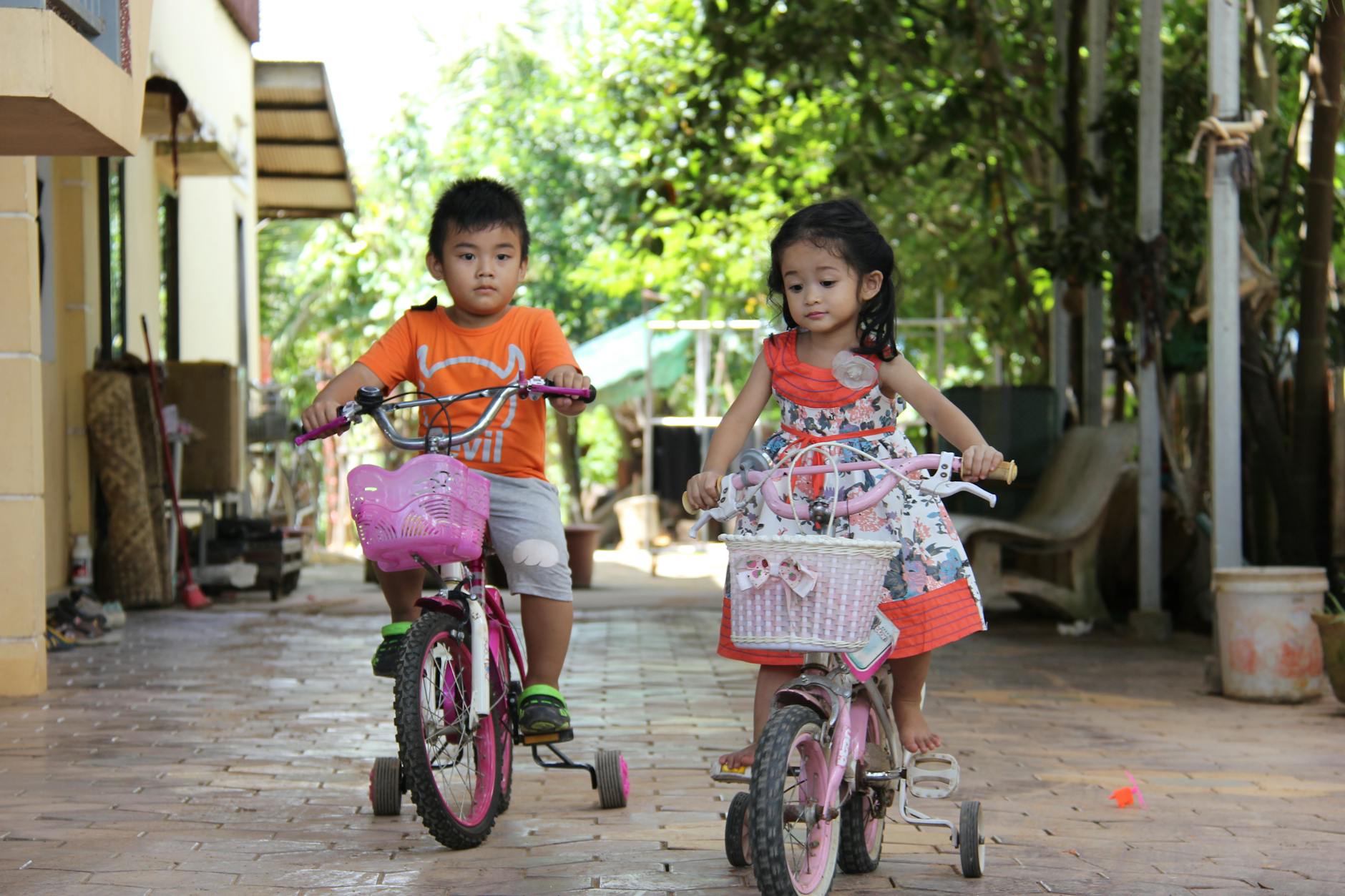 Two young children enjoy riding bicycles outdoors in Krong Siem Reap, Cambodia.