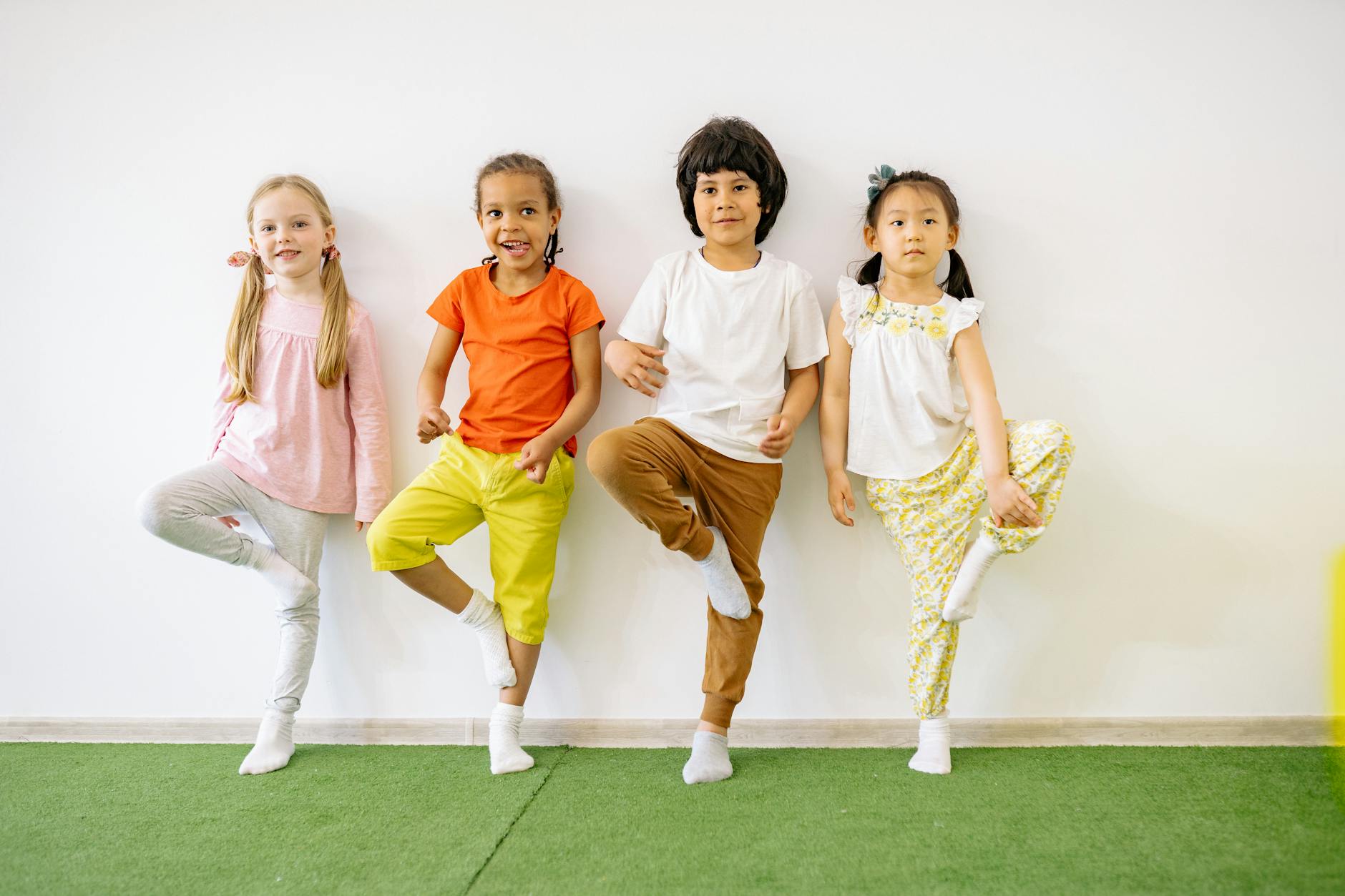 Four children joyfully participating in an indoor balancing exercise, promoting fun and fitness.